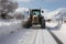 Post-snowstorm scene: Tractor clears road, unveiling its path from the recent snowfall.