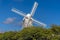 A post windmill protrudes above the hedgerow on the South Downs near Brighton, UK