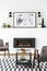 Poster above black fireplace in apartment interior with grey arm