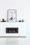 Poster above black fireplace in minimal white living room interior. Real photo