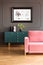 Poster above green cupboard in grey loft interior with pink couch on wooden floor