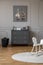 Poster above grey cabinet in kid`s room interior with rocking horse on round rug. Real photo