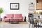 Poster above pink couch in white apartment interior with black c