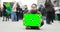 Poster with green screen in man`s hands who is sitting on the street during demonstration.