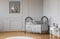 Poster on grey molding wall in baby`s bedroom interior with bed next to white table. Real photo