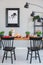 Poster on grey wall in industrial dining room interior with black chairs and lamp at table