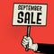 Poster in hand, business concept with text September Sale