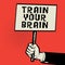 Poster in hand, business concept with text Train Your Brain