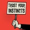 Poster in hand, business concept with text Trust Your Instincts