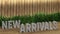 Poster lettering new arrivals. Large letters on a wooden table. Modern decorative grass, backlit wall of wooden battens. Great