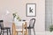 Poster on pastel pink wall of sophisticated dining room interior with round table