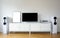 Poster on table in room.Modern audio stereo system with white speakers on bureau in modern interior