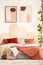 Posters above bed with red pillows and blanket in modern pastel