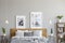 Posters above wooden bed between tables with plants in grey bedroom interior with lamps. Real photo