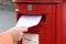 Posting letter to red british postbox