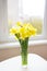 Posy of bright yellow daffodils on white wooden table