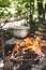 The pot is burning near the tent in the forest at night. Beautiful campfire in a tourist camp in the wild