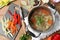 Pot of delicious vegetable bouillon and ingredients on wooden table, flat lay