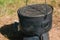 Pot on a metal camp furnace stove on woods outdoors. Close-up.