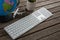 Pot plant, globe, keyboard and airplane model on wooden plank