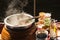 .The pot is prepared for cooking. The noodles are in low-light, boiling water with white smoke and steam on black background