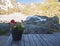 Pot of red and white geranium flowers on wooden table overlooking snow-capped moutain peaks at hiking trail, Stubai