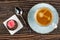 Potato cake with cream on tissue, spoon, cup of coffee on saucer on wooden table. Top view