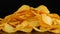 Potato chips lie on a mirror surface randomly scattered on a black background. Harmful food, fast food