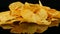 Potato chips lie on a mirror surface randomly scattered on a black background. Harmful food, fast food