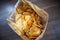 Potato chips in open snack bag closeup on table floor