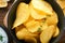 Potato corrugatedchips. Fast food. Crispy potato chips ceramic black bowl with sour cream sauce and onions in wooden stand on old