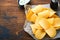 Potato corrugatedchips. Fast food. Crispy potato chips ceramic black bowl with sour cream sauce and onions in wooden stand on old