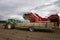 A potato harvester unloading potatoes into wooden bins on a trailer, towed by a tractor