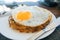 Potato pancakes with fried eggs are served with a knife and fork. On the oak table. Cafe by the sea.