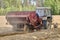 Potato planter attached to farm tractor planting potatoes during field work of planting season.