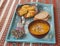 Potato rhombuses with fried onions and pumpkin soup on the tray