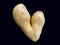 Potato in the shape of a heart. Potato fruits of an unusual shape. Concept: love potatoes. Vegetables isolated on black background