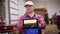 In potato storage warehouse, farmer holding digital tablet in his hands, which shows farm field with young bushes of