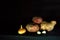Potato tubers, onions and a couple of cloves of garlic lie on a wooden surface on a dark background.