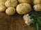 Potato tubers and potato flowers on a wooden surface