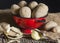 Potatoes in a drainer on an old wooden plank in which there are other potatoes with one peeled potato and a knife