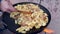 Potatoes fried in a fat on huge black round pan made of cultivators disc.