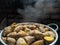 Potatoes with their skins in a stainless steel pot. ripe yam, visible smoke.