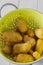 Potatoes, washed, in a bright green metal colander.