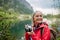 Potrait of active senior woman on hike in autumn mountains taking photos with camera.