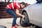 Potrait of young man changing seasonal tires, installing summer tires on automobile