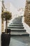 Potted olive tree on grey staircase, white building in the traditional village on Santorini