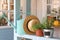 Potted plants, can and straw hat on light blue wooden veranda railing outdoors. Gardening tools