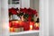 Potted poinsettias, burning candles and festive decor on windowsill in room. Christmas traditional flower