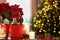 Potted poinsettias, burning candles and festive decor on wooden table in room, space for text. Christmas traditional flower